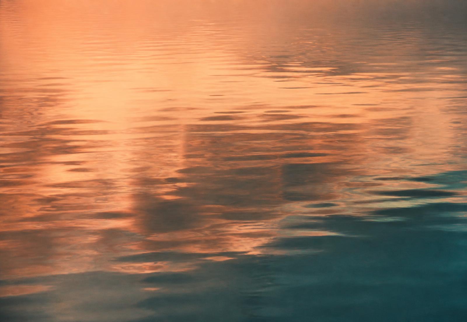Still water at dawn reflecting a warm sky